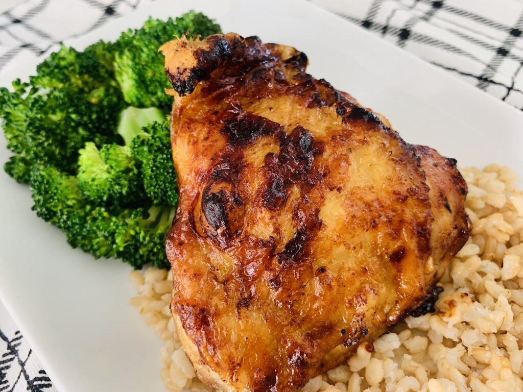 1 air fryer bbq chicken thigh next to a broccoli and on a bed of rice.
