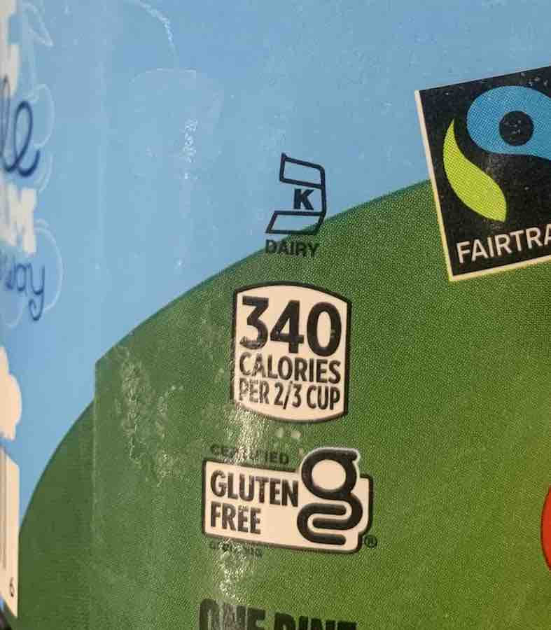 Ben & Jerry's pint, zoomed in on new gluten-free logo: a lowercase "g" with a "c" wrapped around the tail of the "g", the words "gluten free" are to the left of the "g" in black on a white box