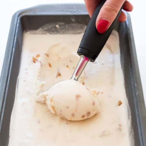 a scooper dipping into a tub of Butter Brickle Ice Cream