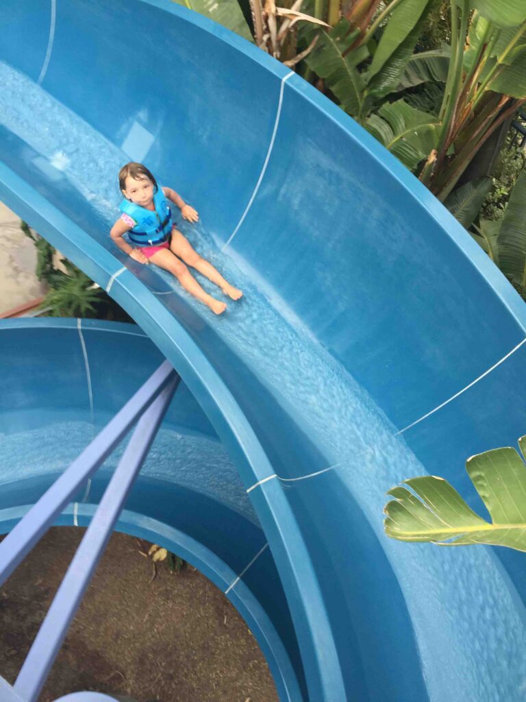 Miss E coming down a. blue water slide