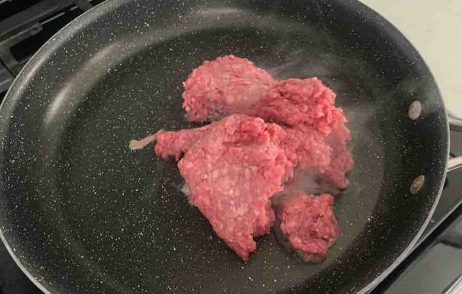 ground beef being cooked in a large pan