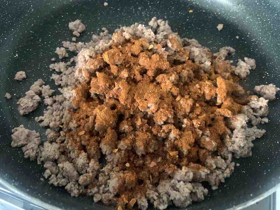 cooked ground beef in a frying pan, covered with taco seasoning (not yet mixed in)