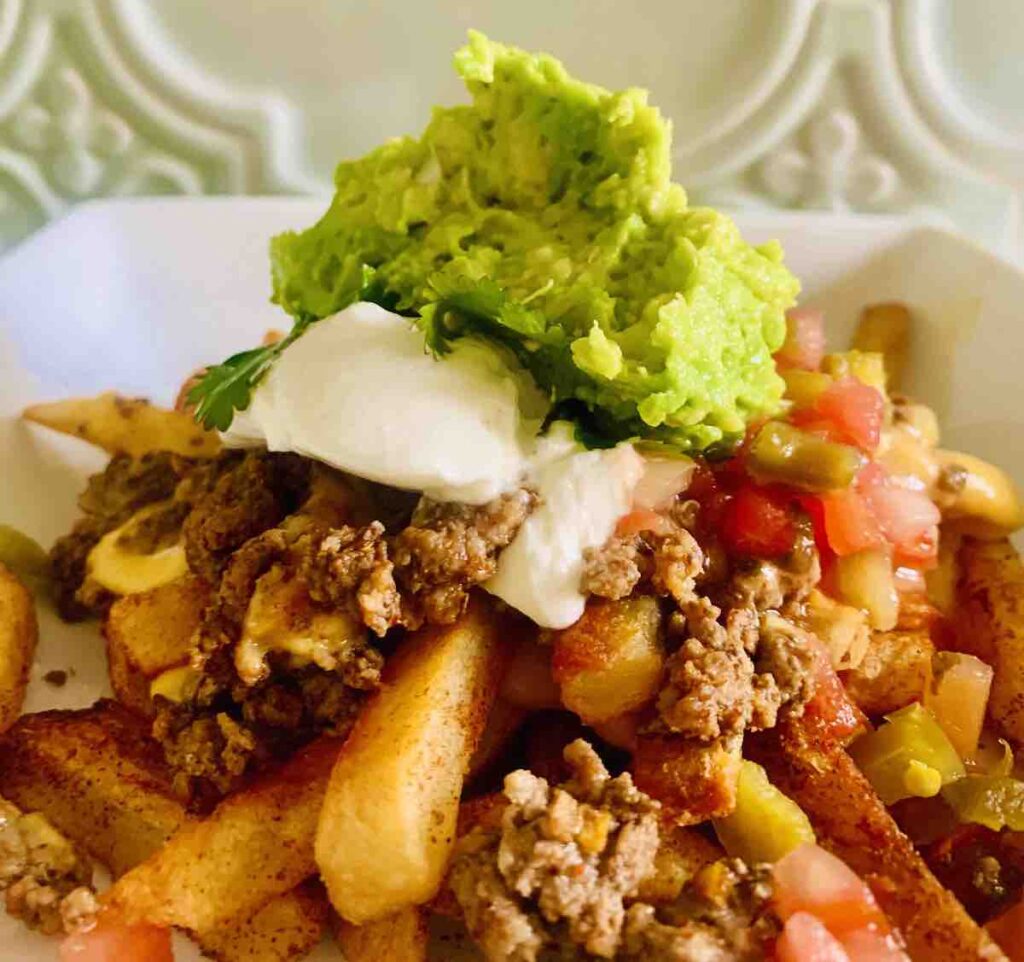 nacho fries topped with ground beef, salsa, sour cream, cilantro and guacamole