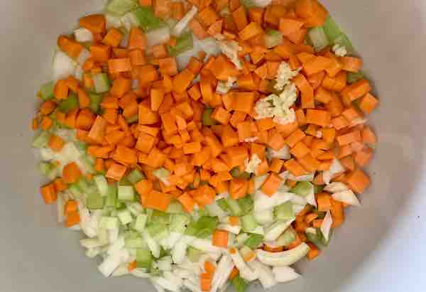 diced carrots, celery, onion, and minced garlic in the bottom of a pot (bird's eye view)