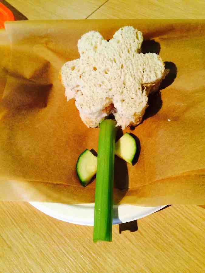 a gluten-free, flower-shaped sandwich, with a celery stalk stem and pieces of zucchini for petals, from Beansprouts