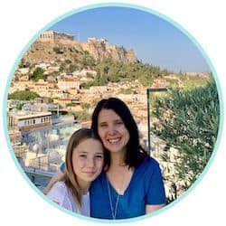 circular photo in a light blue frame: Miss E in a white shirt and Heather in a bright blue shirt, with Acropolis hill in Athens in the background
