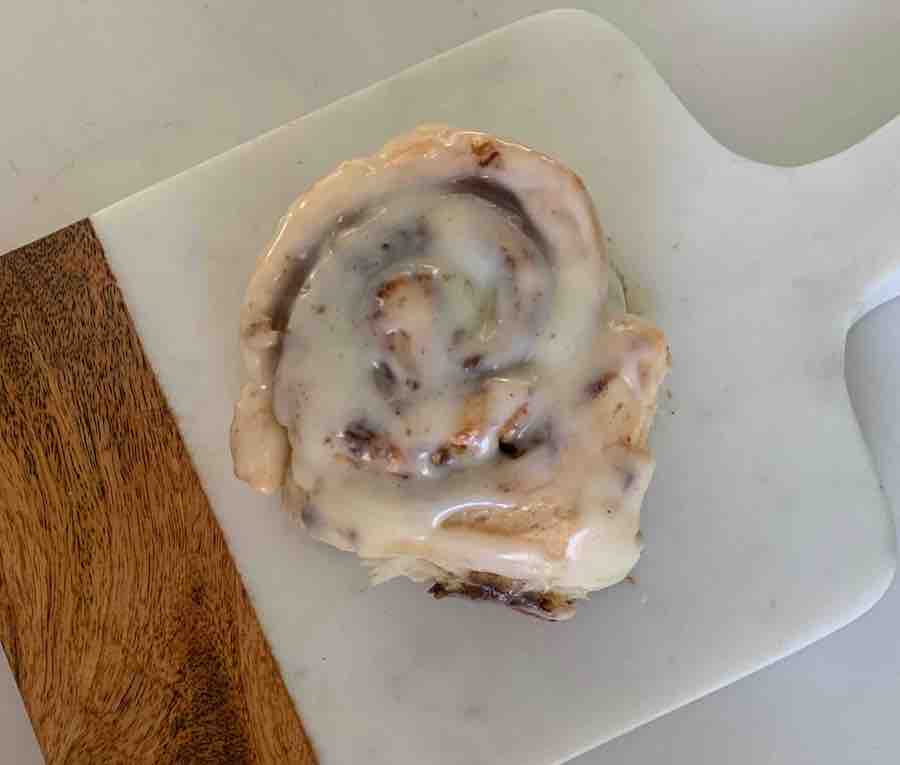 overhead view of a gluten-free cinnamon roll on a wood and marble cutting board