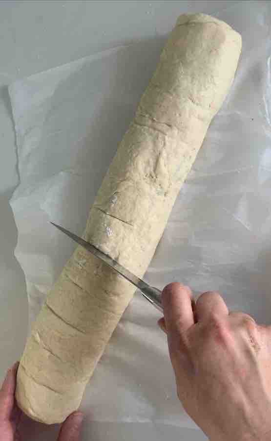 knife scoring log of gluten-free dough to mark where to cut cinnamon roll discs out of log