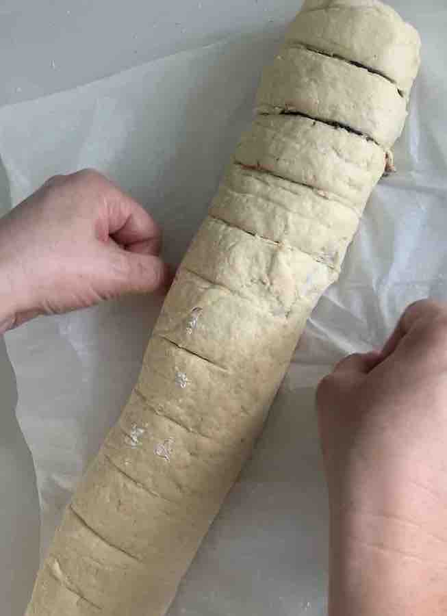log of gluten-free dough, two hands sliding thread under the log 