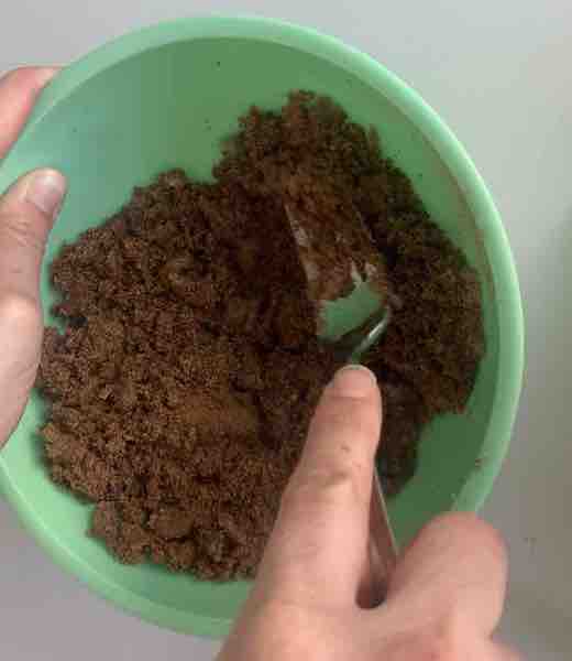 small green bowl with crumbly cinnamon, sugar, butter mixture, being mixed by a fork