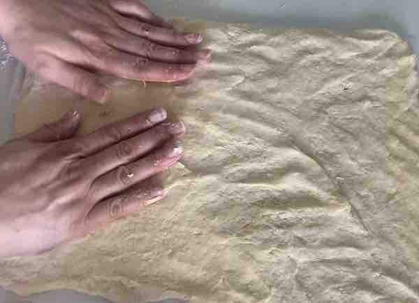 gluten-free dough being pressed into a rectangle by two hands