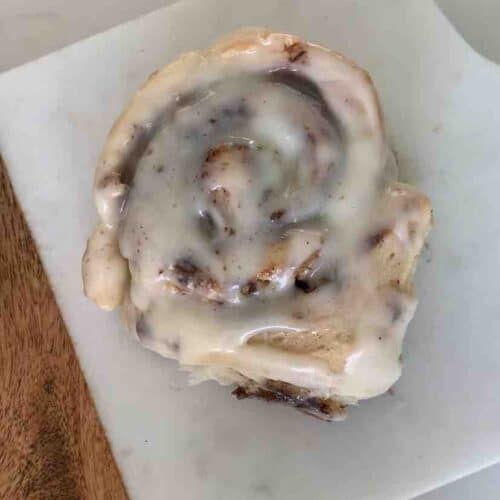 overhead view of a gluten-free cinnamon roll on a wood and marble cutting board