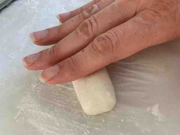 hand rolling out a piece of dough into a rope