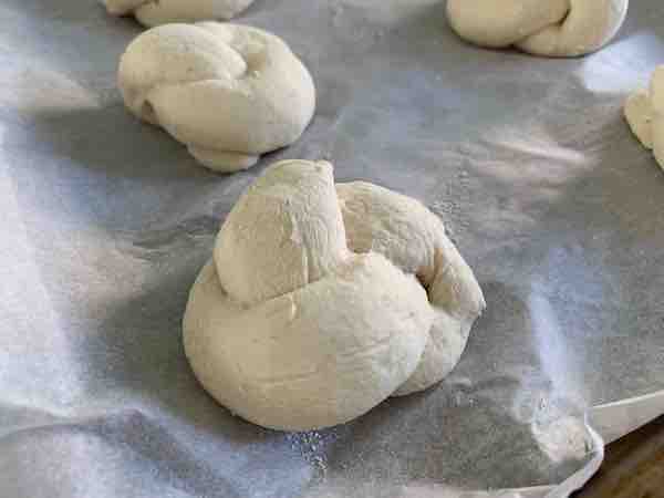 gluten-free garlic knot dough on a baking sheet, puffed up after rising