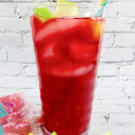 iced passion tea lemonade, vibrant fascia, visible ice, rainbow straw and sliced green apples and lemons