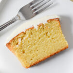 slice of gluten-free lemon loaf topped with white icing, fork in the background