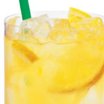orange refresher in a glass with orange slices, ice, and a green straw