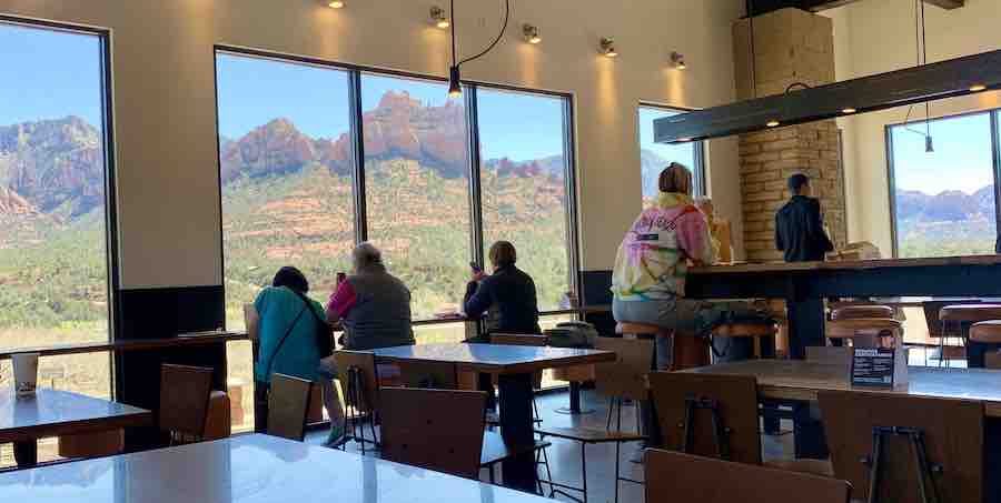 inside Chipotle with tables, chairs, a handful of guests, and floor to ceiling windows showing off red rock views