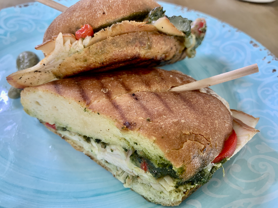 two halves of a pesto chicken panini on a blue plate, panini-maker lines visible on the bread