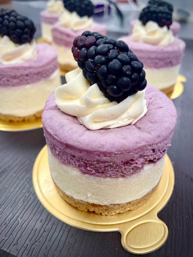 individual blackberry lemon cheesecake with whipped cream and a blackberry on top