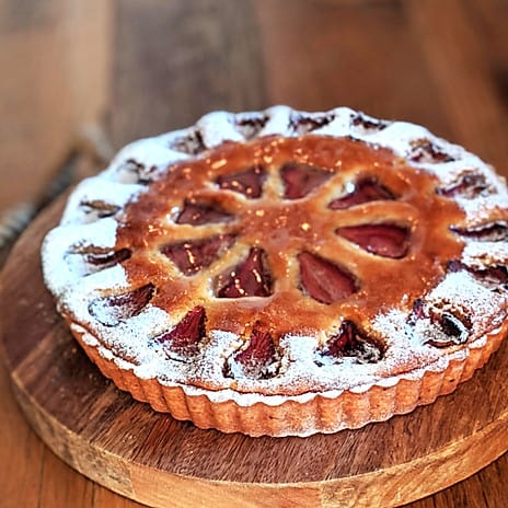 a fruit tart with symmetrical heart beautifully symmetrical tear-drop shaped cut outs in two circles along the top crust, with powdered sugar along the outer circle