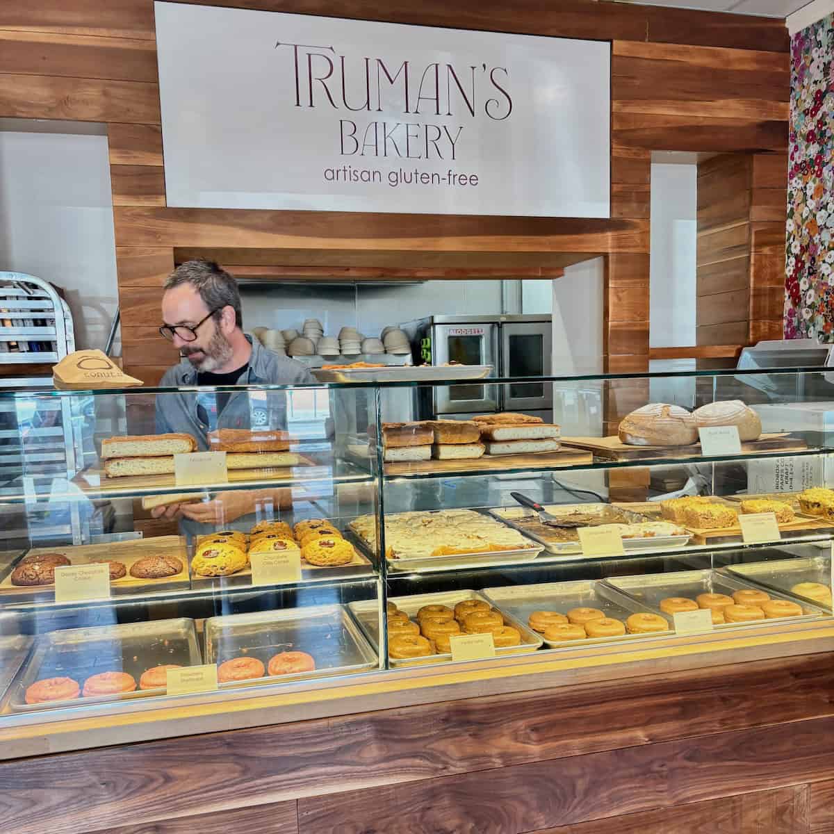 Truman's Bakery above a bakery displace case filled with baked goods with a man working behind the counter