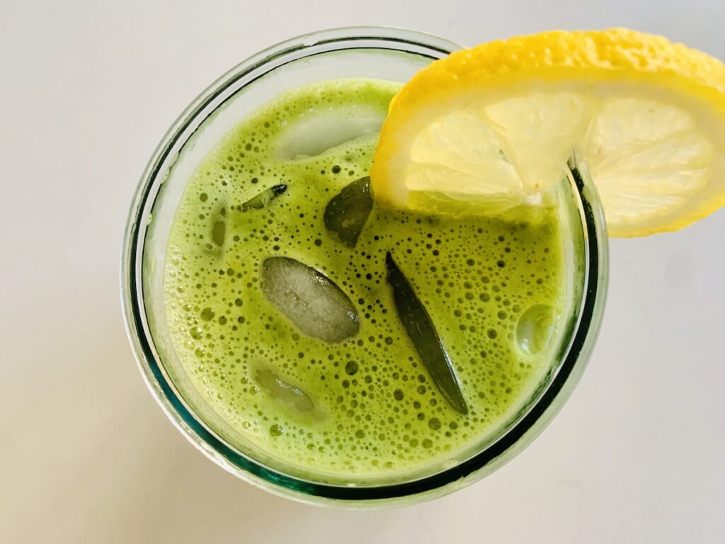 top view of bright green matcha lemonade in a glass of ice with a lemon slice on the rim