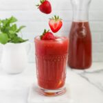 strawberries falling into a glass of strawberry açaí lemonade