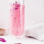 bright pink dragon drink in a tall glass, fascia colored dried dragon fruit pieces on the white counter