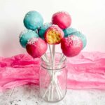 bright pink and blue cake pops in a glass mason jar, bite taken out of one of the pink cake pops