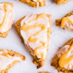 pumpkin scones topped with white icing and caramel drizzle