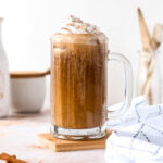 iced pumpkin latte, in a glass mug, topped with whipped cream