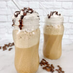 2 Frappuccinos in tall glass jars, topped with whipped cream and chocolate drizzle