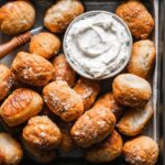 a pile of gluten-free pretzel bites and a small bowl of white dipping sauce