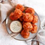 a plate of buffalo turkey meatballs and a bowl of white dipping sauce and toothpicks