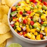 a bowl of corn mango salsa with chips next to it