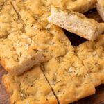 a large focaccia bread cut into pieces, the side of one piece is showing to demonstrate it is airy