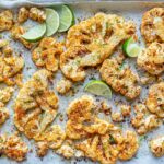 roasted cauliflower on a baking sheet with lime slices