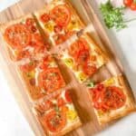 a tomato tart cut into six squares on a wooden cutting board