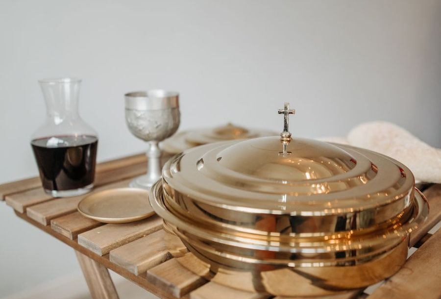 a communion table with wine/juice, a cup and communion wafer tray with lid