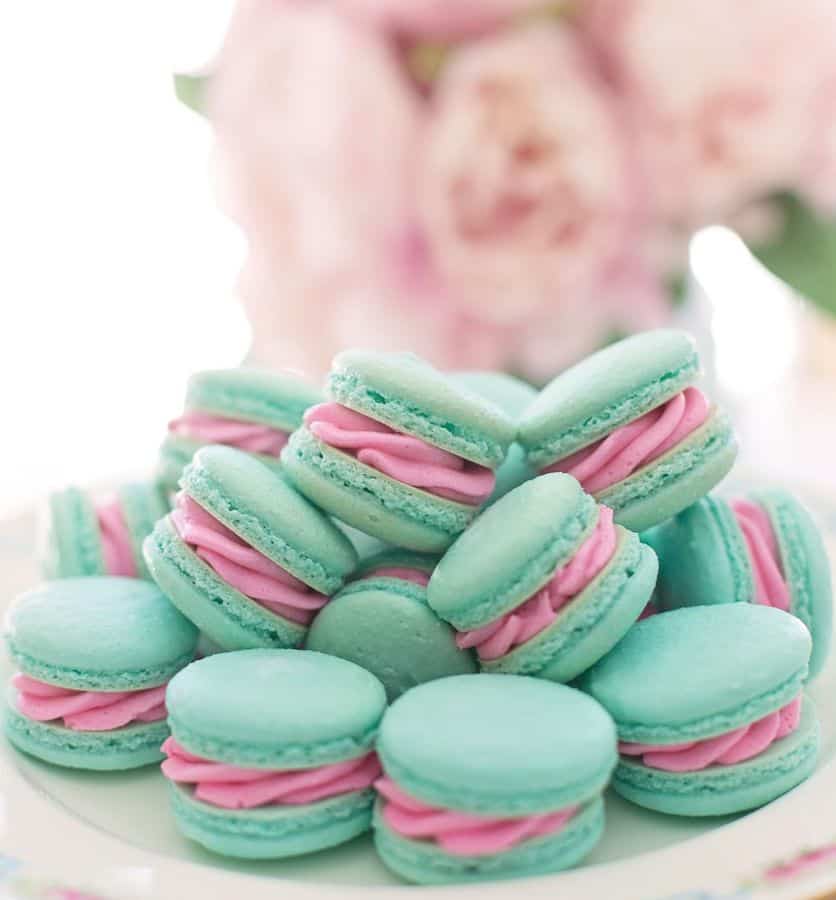 aqua macarons with pink filling, bouquet of pink roses in the background