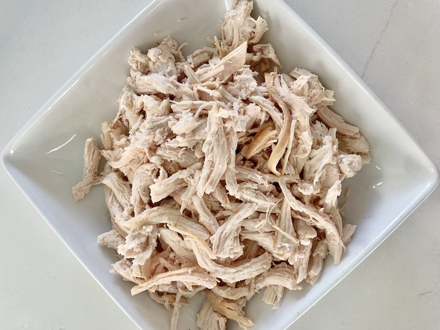 shredded chicken in a white, square bowl