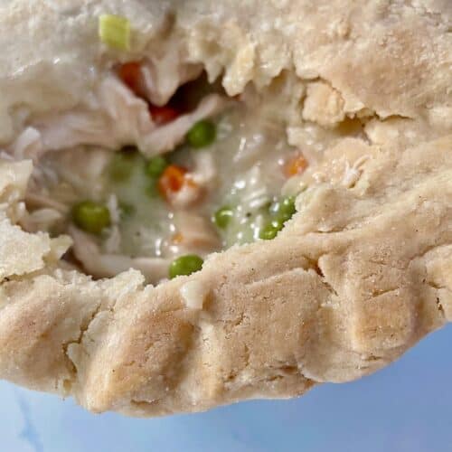 edge of gluten-free chicken pot pie showing golden brown ridged edge and piece of the crust missing to show the filling