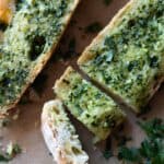 French bread topped with garlic butter and parsley, two cut slices