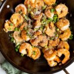 a pan full of cooked shrimp, topped with herbs