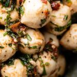 mozzarella balls in a dish, marinated with spices and tomatoes