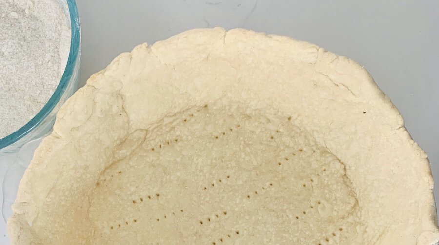 birds eye view of part of a parbaked pie crust with fork dimples along the bottom