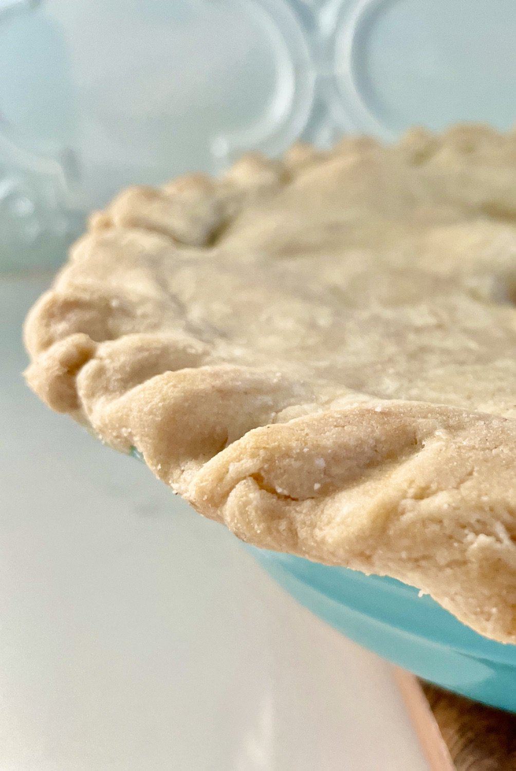 close up, partial, side of a gluten-free pie crust in a teal pie pan