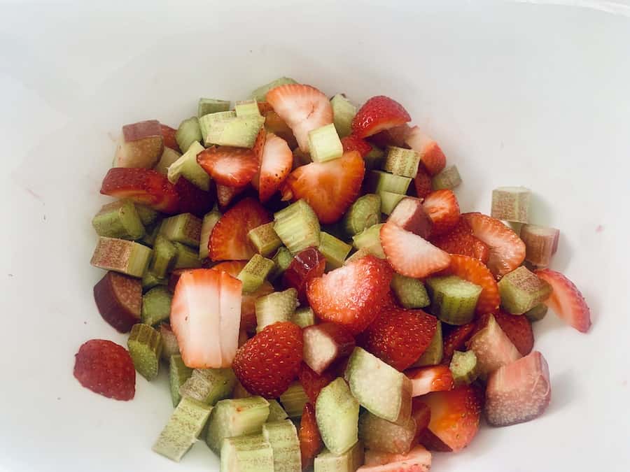 sliced red strawberries and green and red/pink rhubarb in a bowl