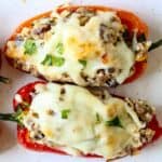 2 red mini peppers stuffed with sausage and topped with white cheese